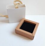جعبه‌های جواهرات با روبان دار در واقع برای نگهداری و حمل آسان جواهرات طراحی شده‌اند. این جعبه‌ها علاوه بر اینکه جواهرات را درون خود نگهداری می‌کنند، دارای یک روبان یا دسته هستند که به شما این امکان را می‌دهد که آن را به صورت آسان و راحت بر دوش یا به دستتان بگیرید. از جعبه‌های جواهرات با روبان دار به طور گسترده برای محافظت و نگهداری انواع جواهرات استفاده می‌شود از جمله مروارید، زنجیره‌ها، انگشترها، دستبندها، گوشواره‌ها و غیره. داشتن یک جعبه با روبان دار می‌تواند به شما کمک کند تا جواهرات خود را در دسترس داشته باشید و از خطرات خوردگی، خراشیدگی یا از دست رفتن آنها در اثر نادرست نگهداری جلوگیری کنید. علاوه بر این، از جعبه‌های جواهرات با روبان دار برای هدیه دادن جواهرات به دیگران نیز بسیار استفاده می‌شود. زمانی که شما می‌خواهید یک هدیه شیک و زیبا به دوست یا خانواده‌اتان بدهید، جعبه با روبان دار می‌تواند به عنوان بسته‌بندی جذاب برای جواهرات شما خدمت کند و جواهرات را به شکلی شیک و زیبا به گیرنده‌ی هدیه نشان دهد.